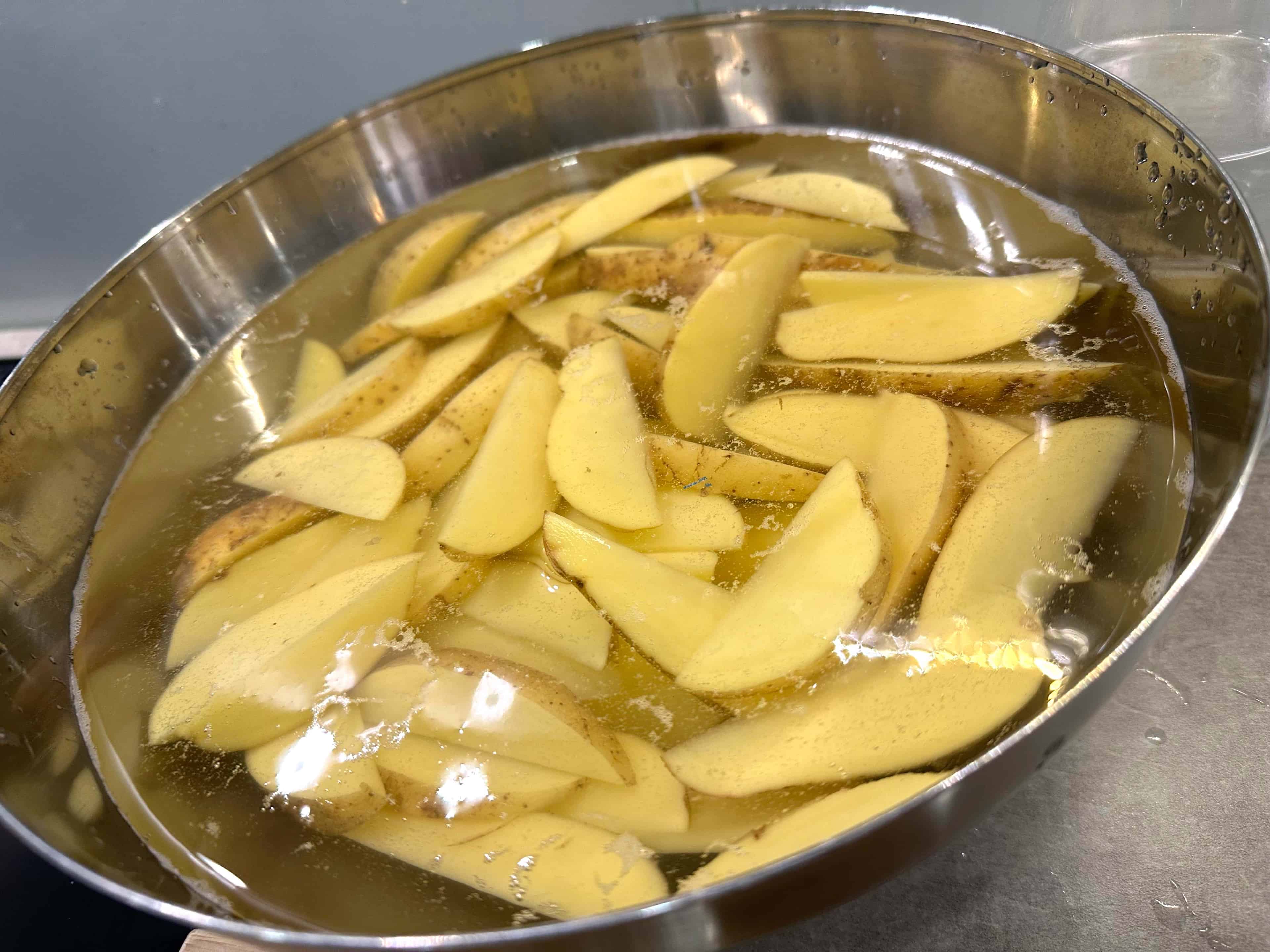 Perunat likoamassa kylmässä vedessä Perunat likoavat kylmässä vedessä, jolloin niistä tulee uunissa rapeampia.